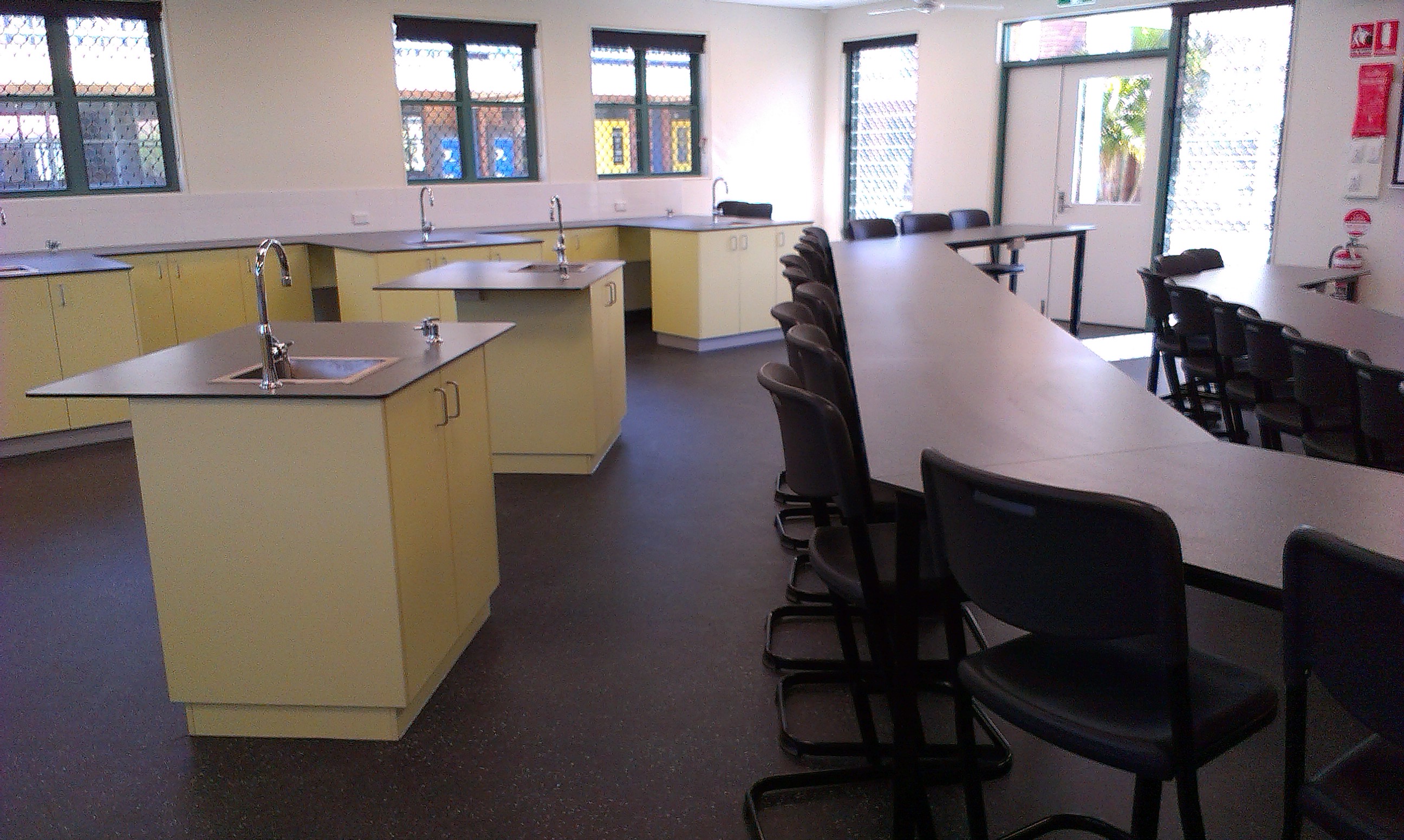 Science classroom with lab benches, sinks, stools and bright natural light from surrounding windows