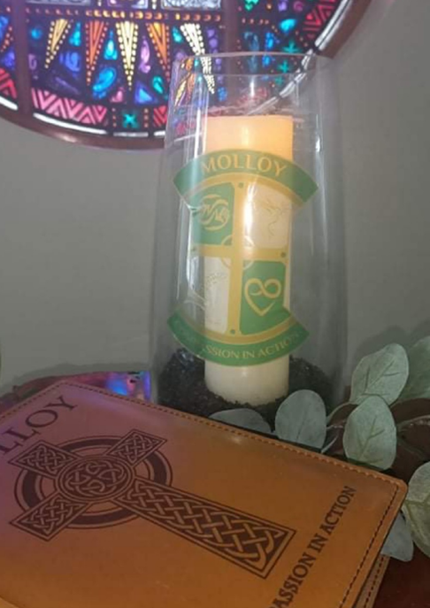 Group of students standing and kneeling in front of a colourful brick-style display on a brick wall