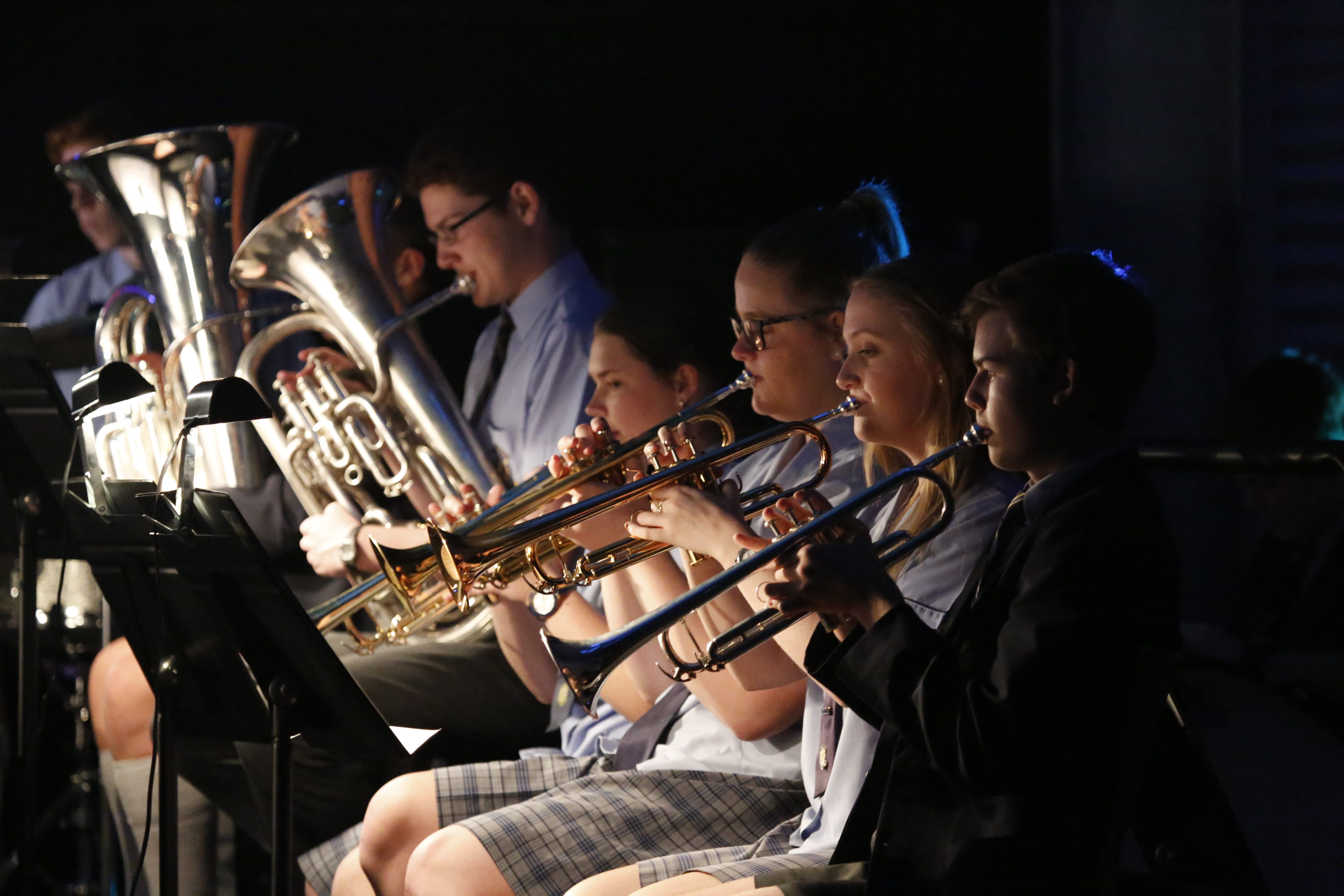 Students in school uniforms playing brass instruments in a seated ensemble