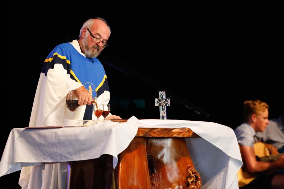 Priest preparing communion at a covered wooden altar